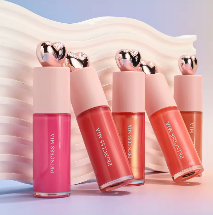 Set of Princess MIA lip glosses with pink and red shades on a soft fabric background