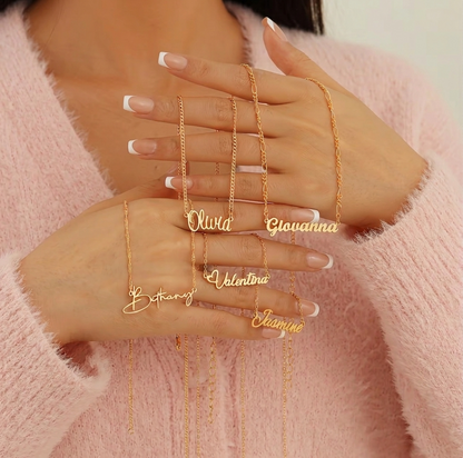 Gold name necklaces on a hand with a pink background