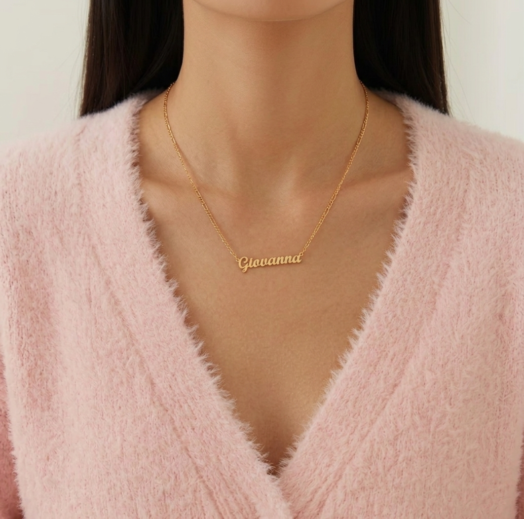 Gold name necklace with 'Giovanna' on a person wearing a pink sweater.